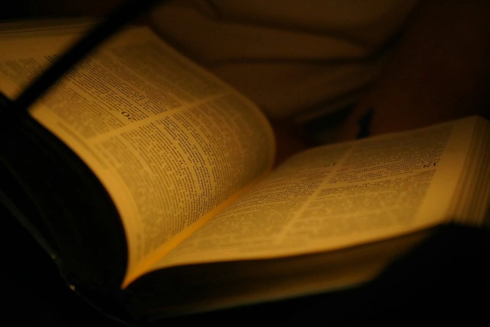An open book illuminated by warm light.