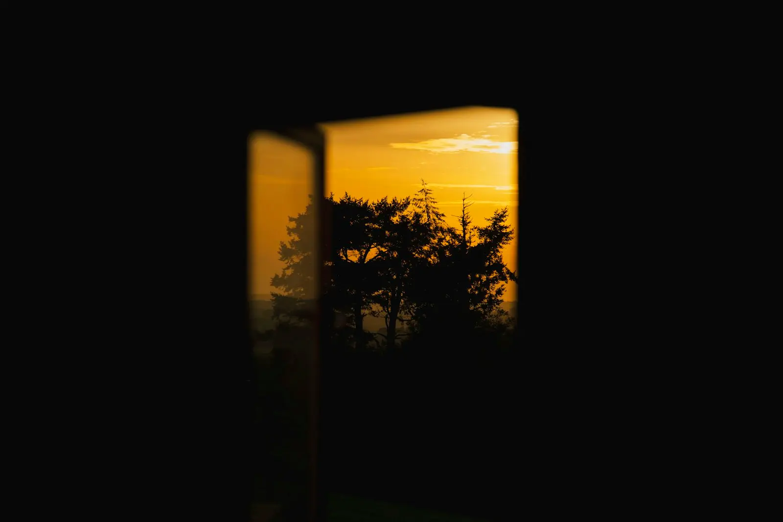 Sunset viewed through a dark window frame.