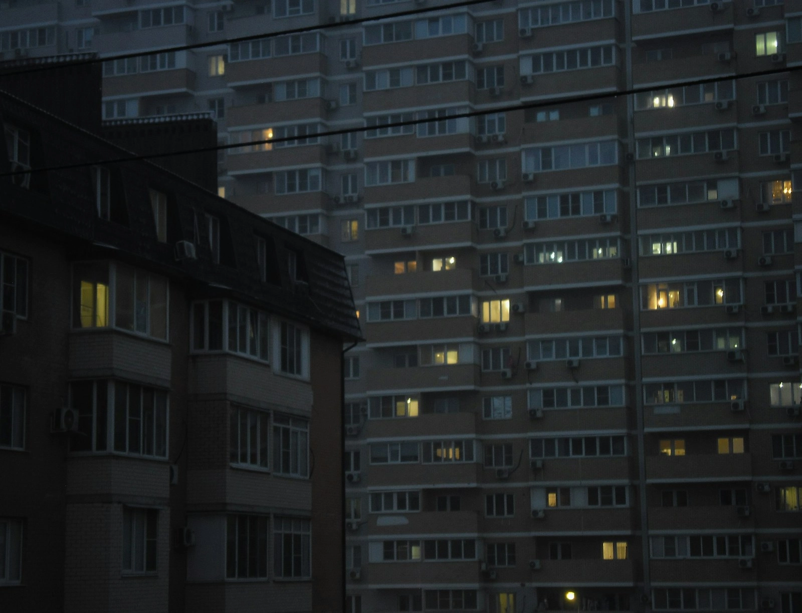 Apartment buildings with glowing windows at dusk.