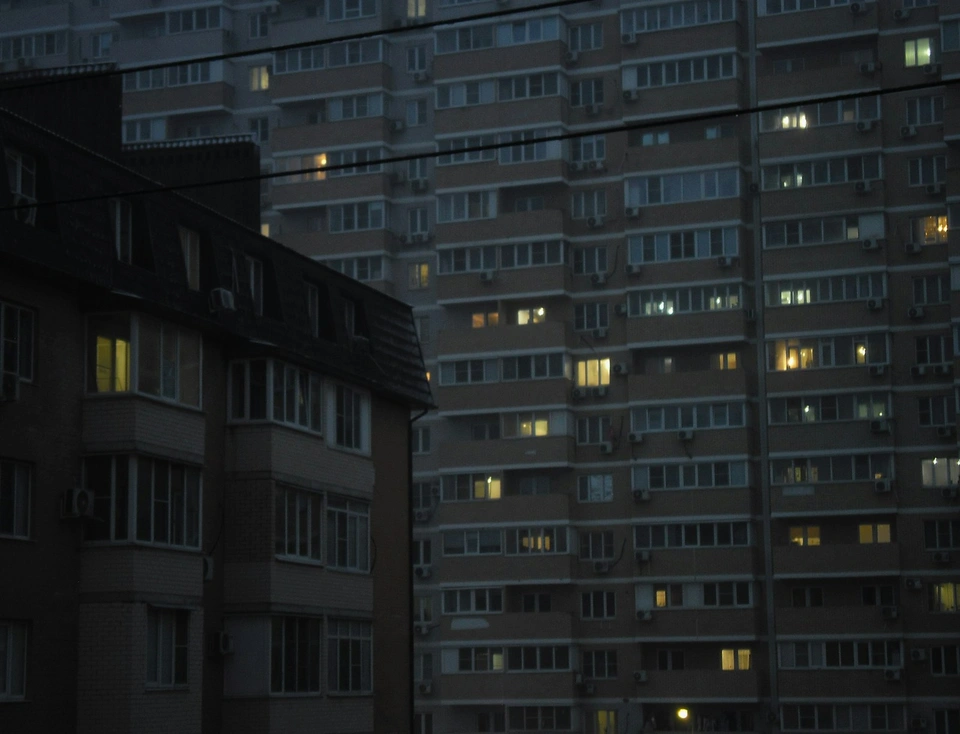 Apartment buildings with glowing windows at dusk.