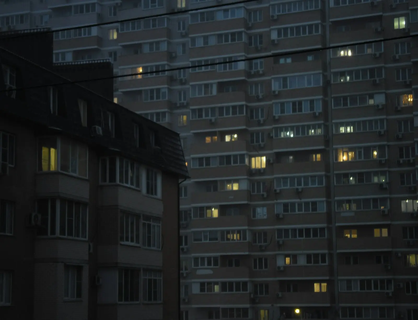 Apartment buildings with glowing windows at dusk.