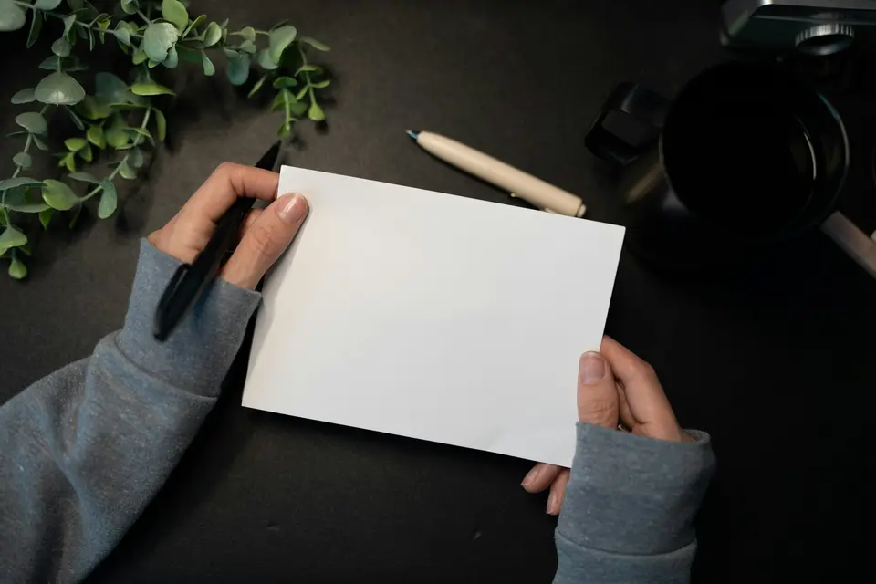 Hands holding blank card with pen and plant